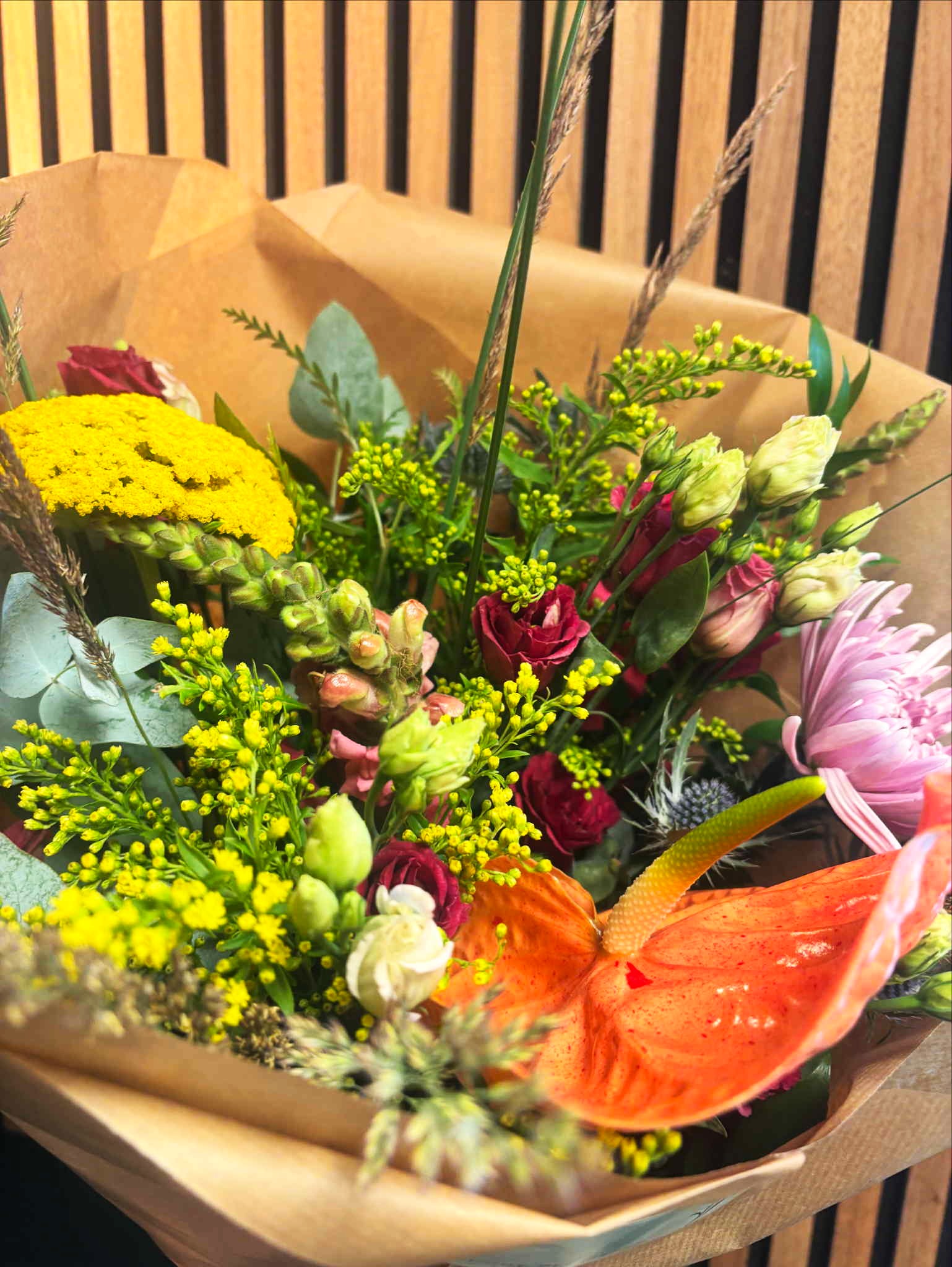 En livlig og vild buket med blomster i stærke farver som gul, orange, rød, lilla og grøn. 