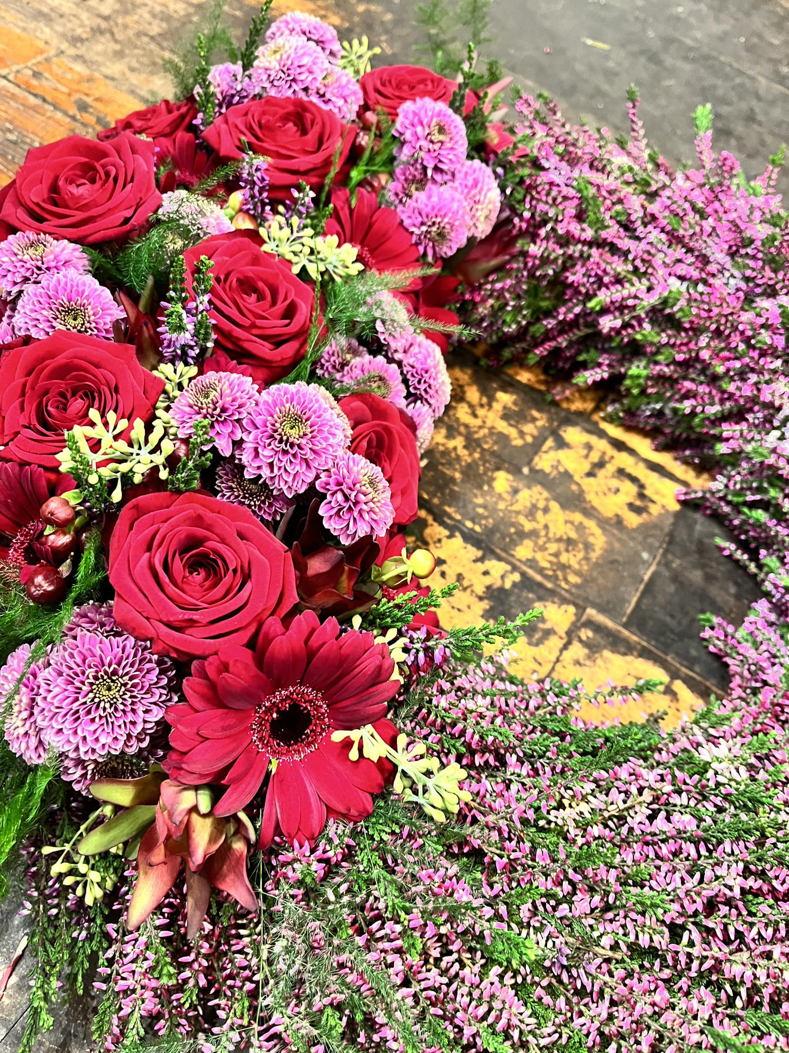 Begravelseskrans bundet med lyserøde lyng, røde roser og gerbera. 