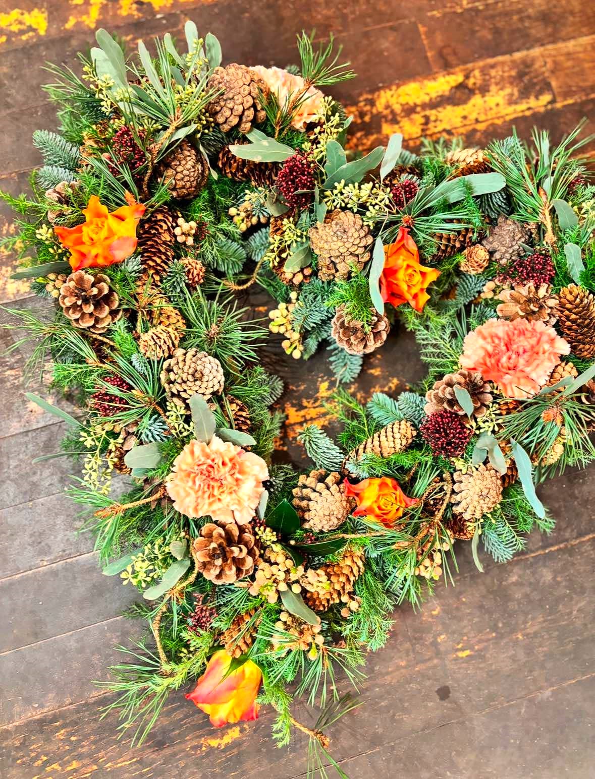 Vinterhjerte med gran, kogler og blomster i gyldne nuancer. 