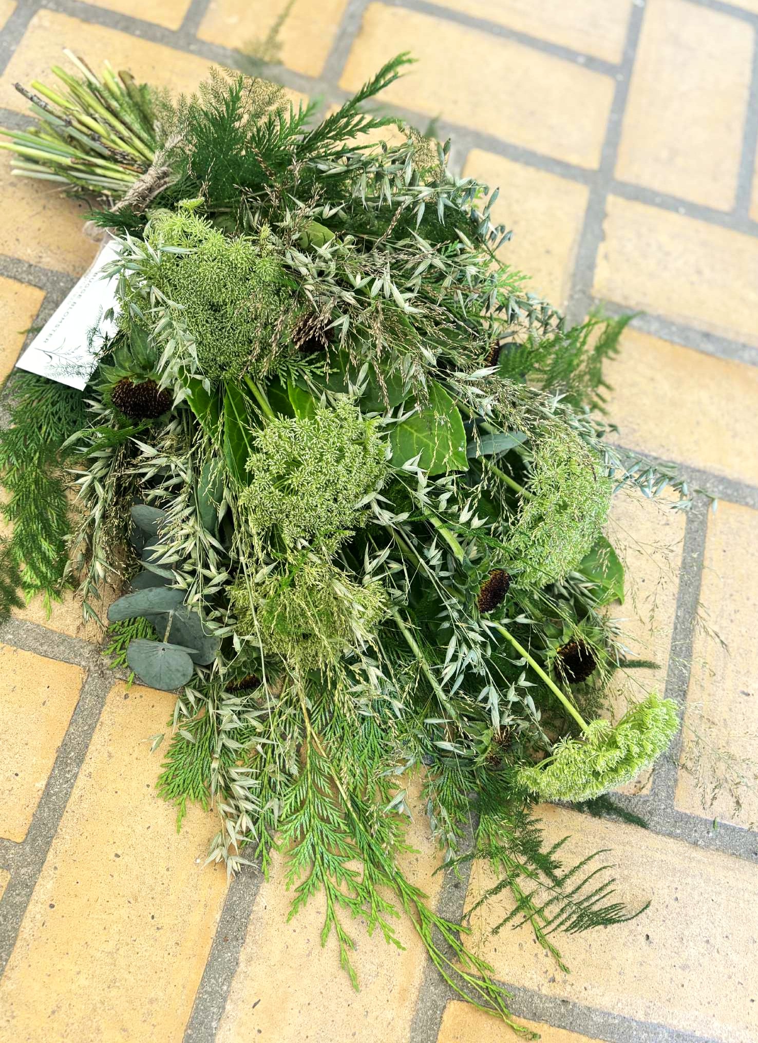 Bårebuket bundet i vildt og naturligt udtryk, med blomster i grønne nuancer. 