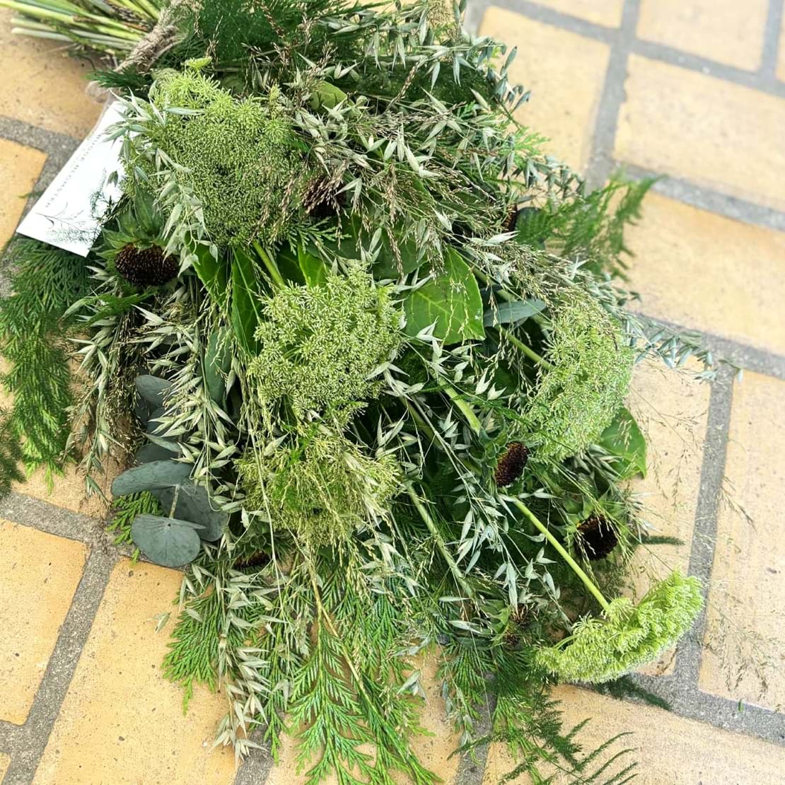 Bårebuket bundet i vildt og naturligt udtryk, med blomster i grønne nuancer.