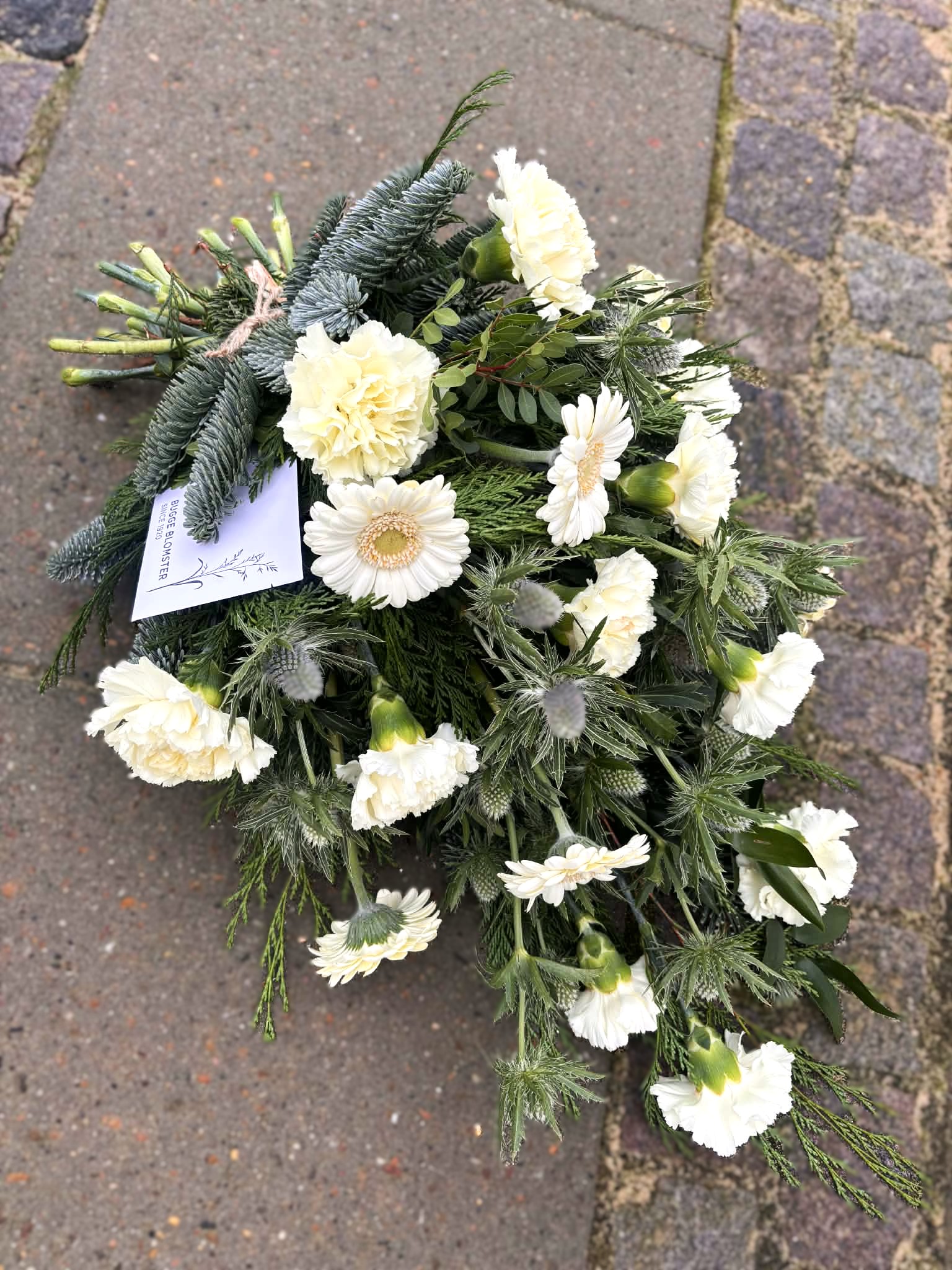 Bårebuket bundet med hvide blomster og grønt. 