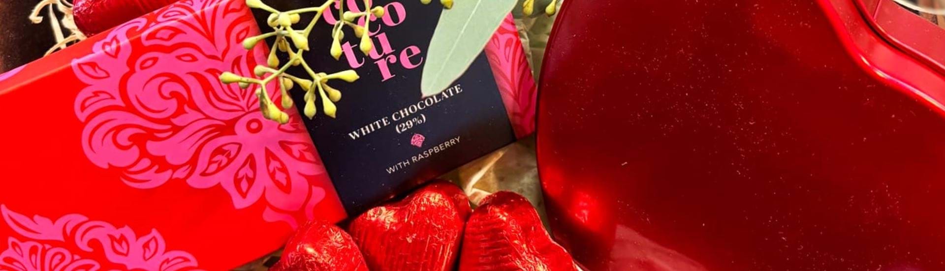 Gavekurv i romantiske røde farver og æsker fyldt med lækker chokolade.