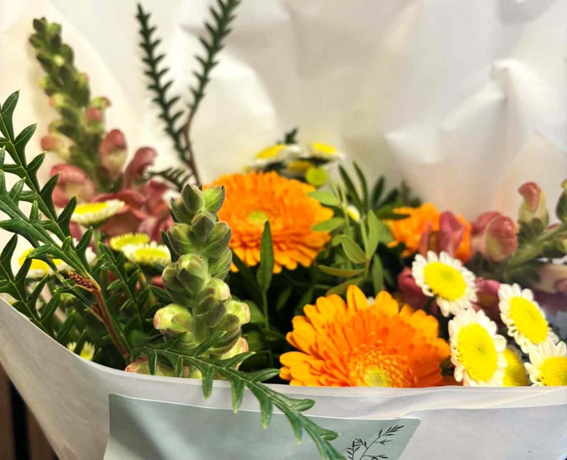 Efterårsbuket bundet med blomster i varme og skarpe gule, orange og rødlige farver. Buketten er bundet luftig og livlig.