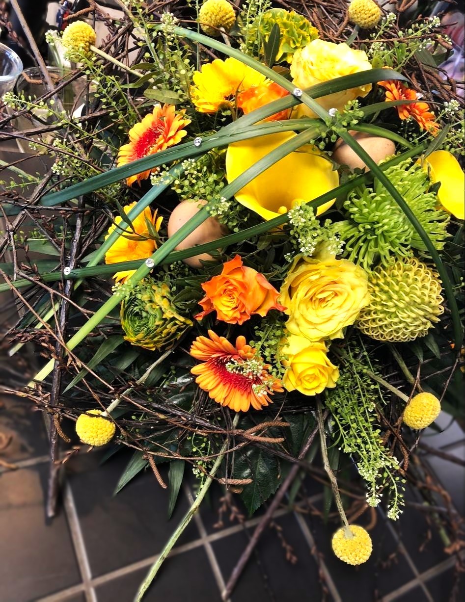 Vild og kreativ påskebuket i gule og orange nuancer med små æg.