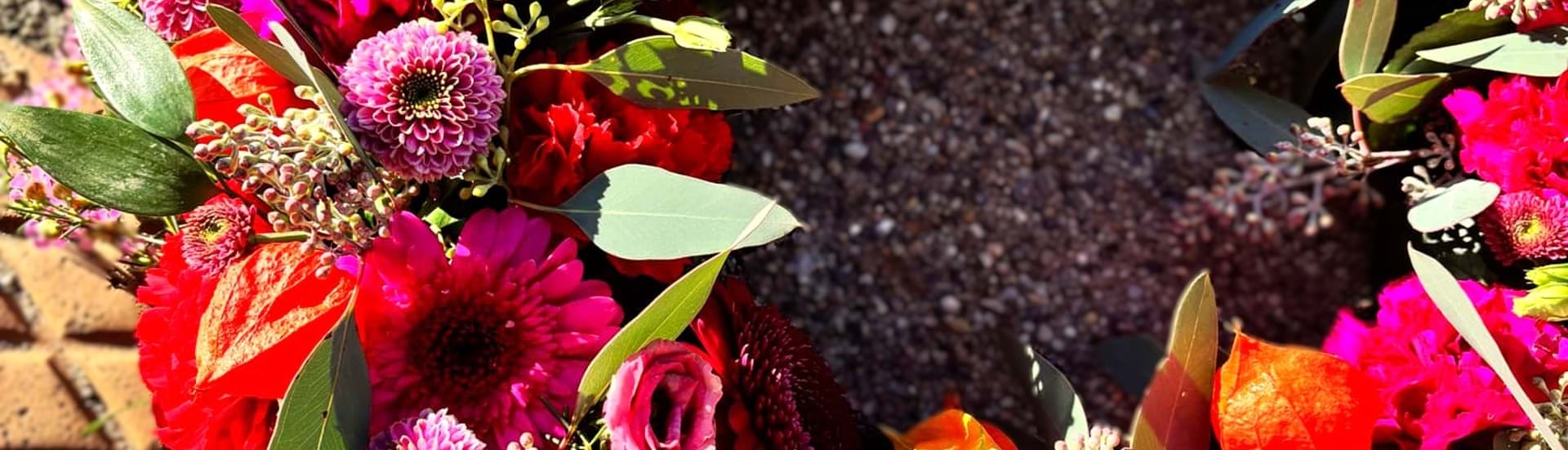 Begravelseskrans bundet med små og store blomster i varme efterårsfarver.