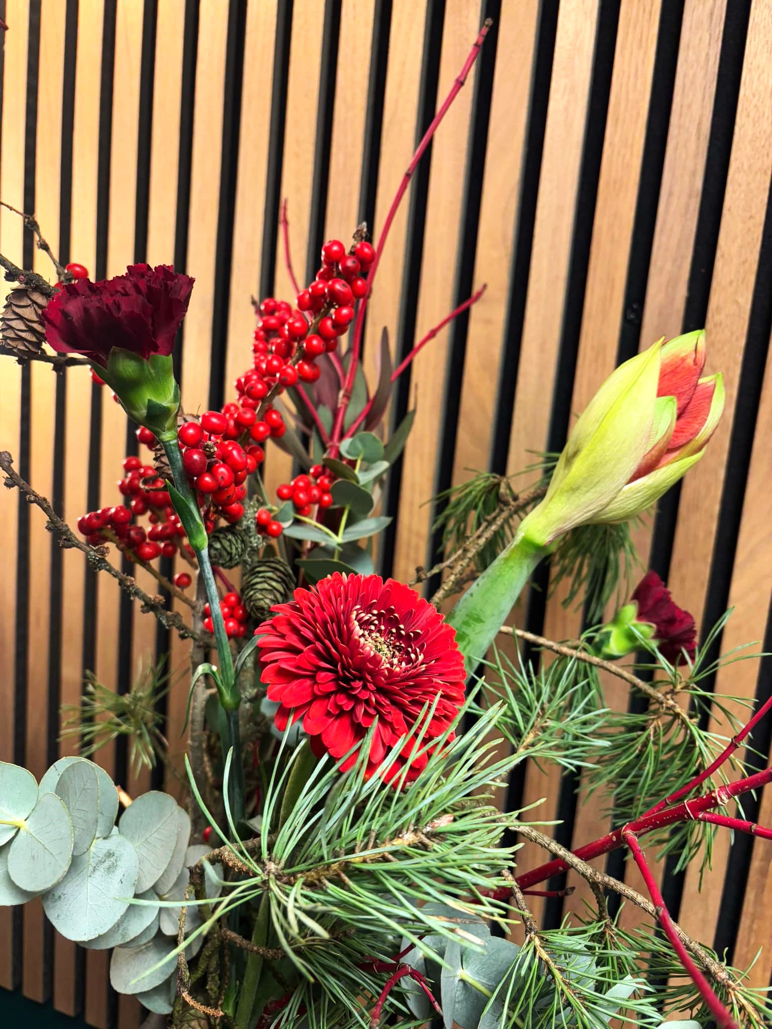 Enkel vinterbuket bundet med gran, røde roser, amaryllis og bærgrene. 