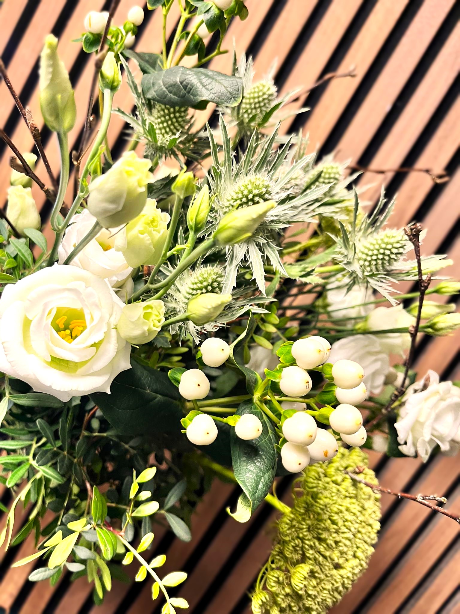 Kondolencebuket i lyse farver og en træpanel baggrund