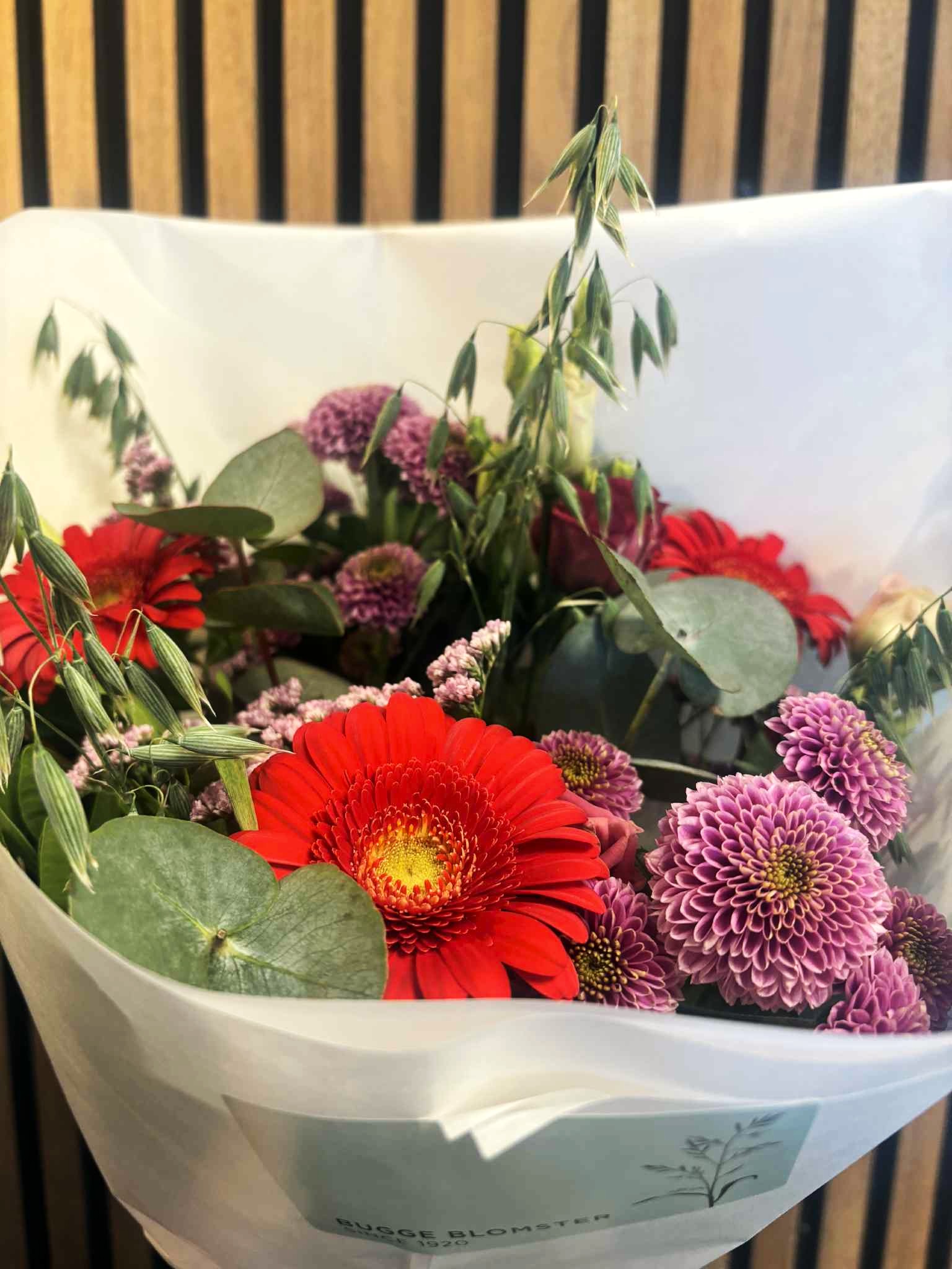 Buket bundet med blomster i varme røde og rosa nuancer. 