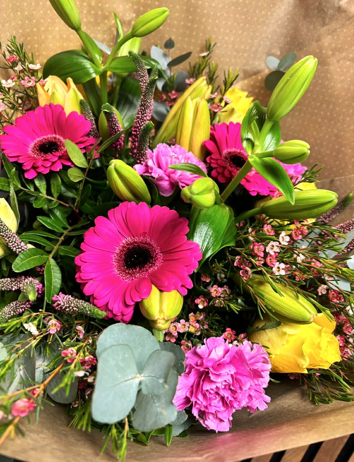 Farverig blomsterbuket i pink, gul og grønne nuancer med friskt og moderne udtryk fra Bugge Blomster.