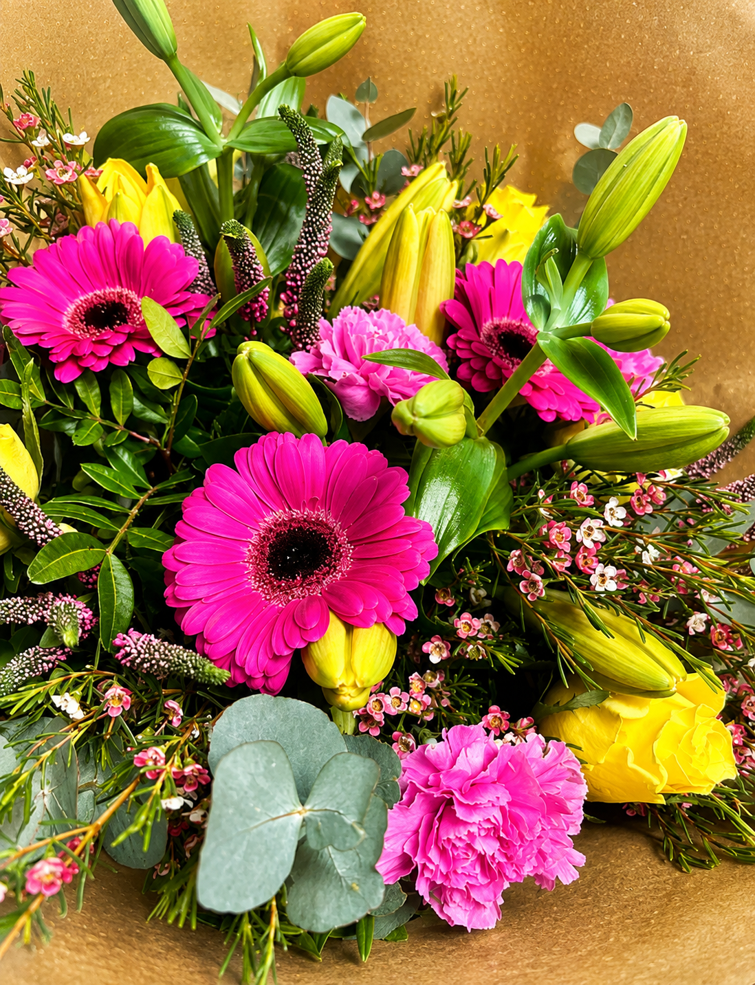 Farverig blomsterbuket i pink, gul og grønne nuancer med friskt og moderne udtryk fra Bugge Blomster.