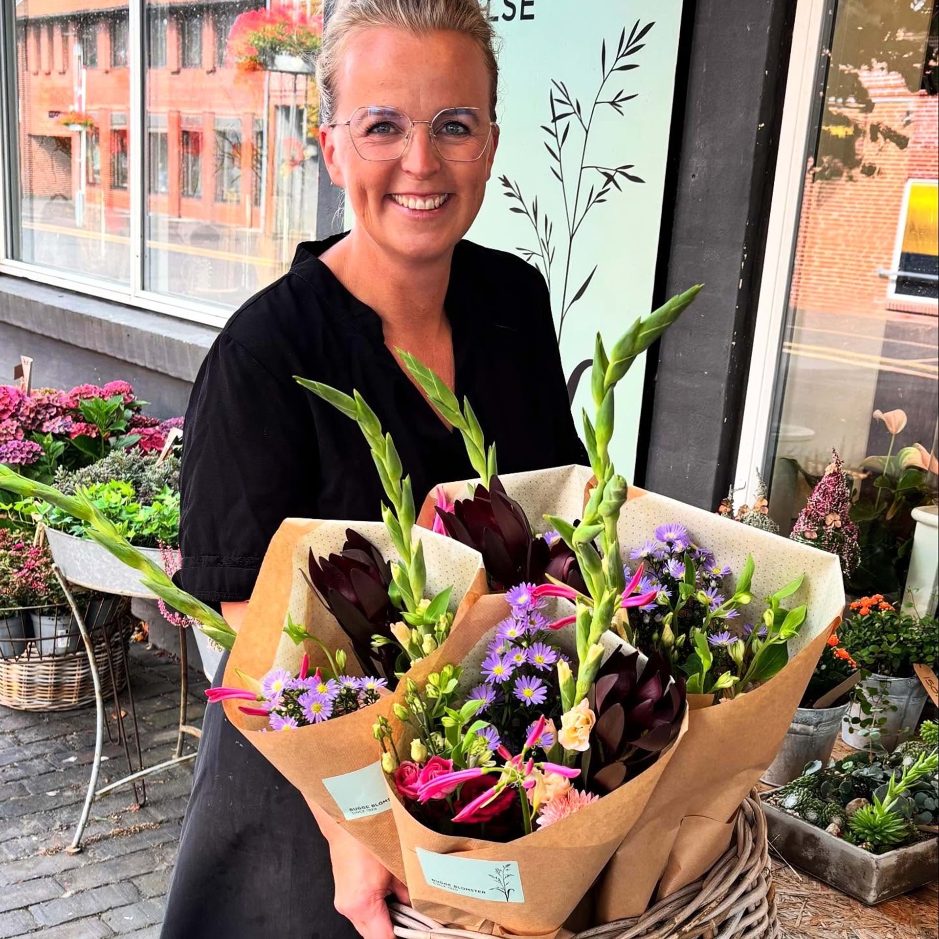 Indehaver Tina Dam holder en fletkurv fyldt med buketter.