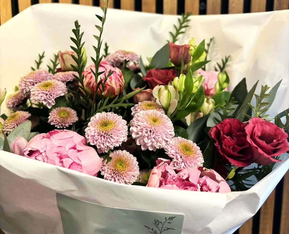 Romantisk buket med blomster i rosa, røde og lune nuancer.