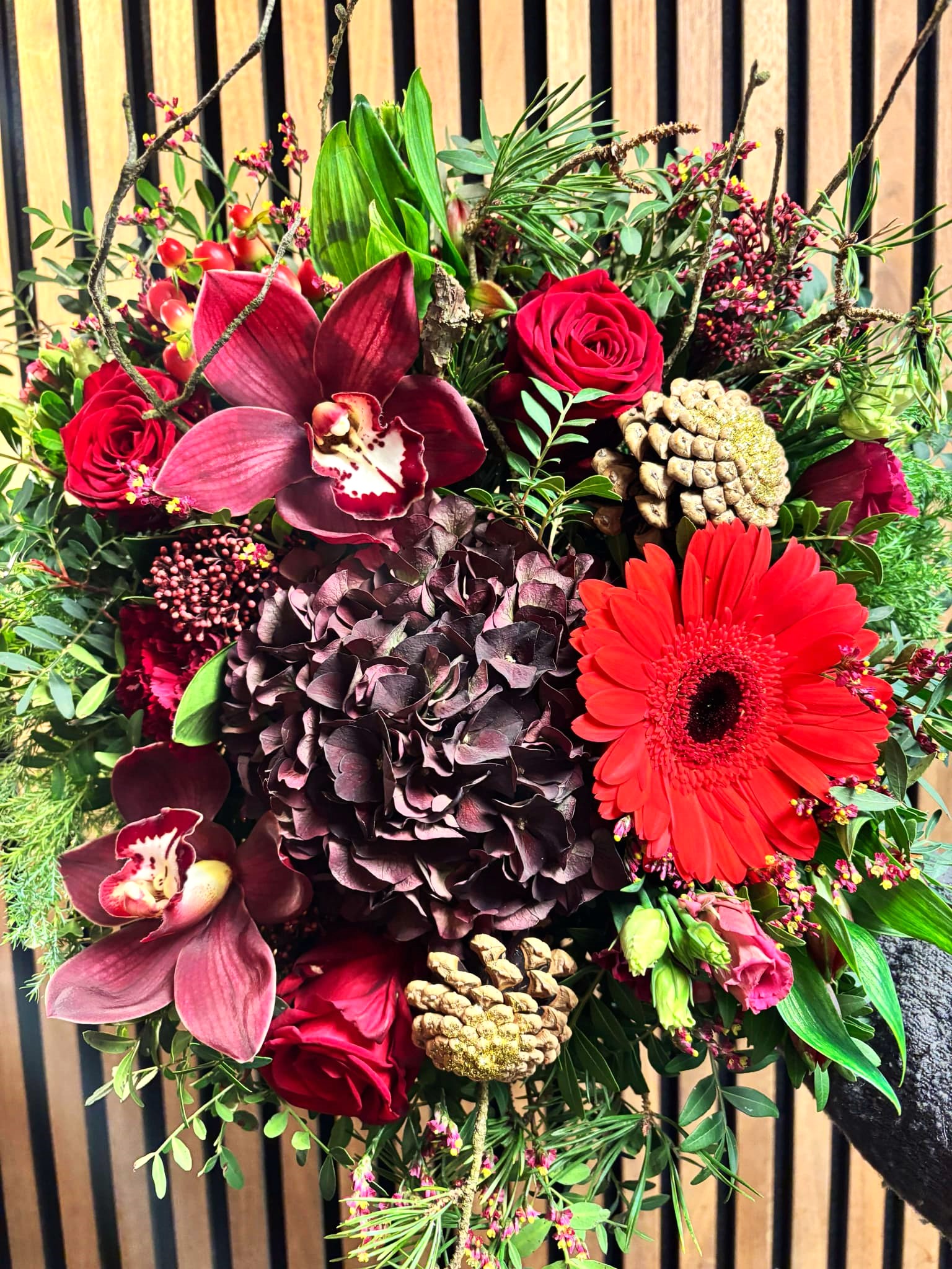 Rød julebuket med hortensia, orkidéer, kogler, røde roser og gran. 