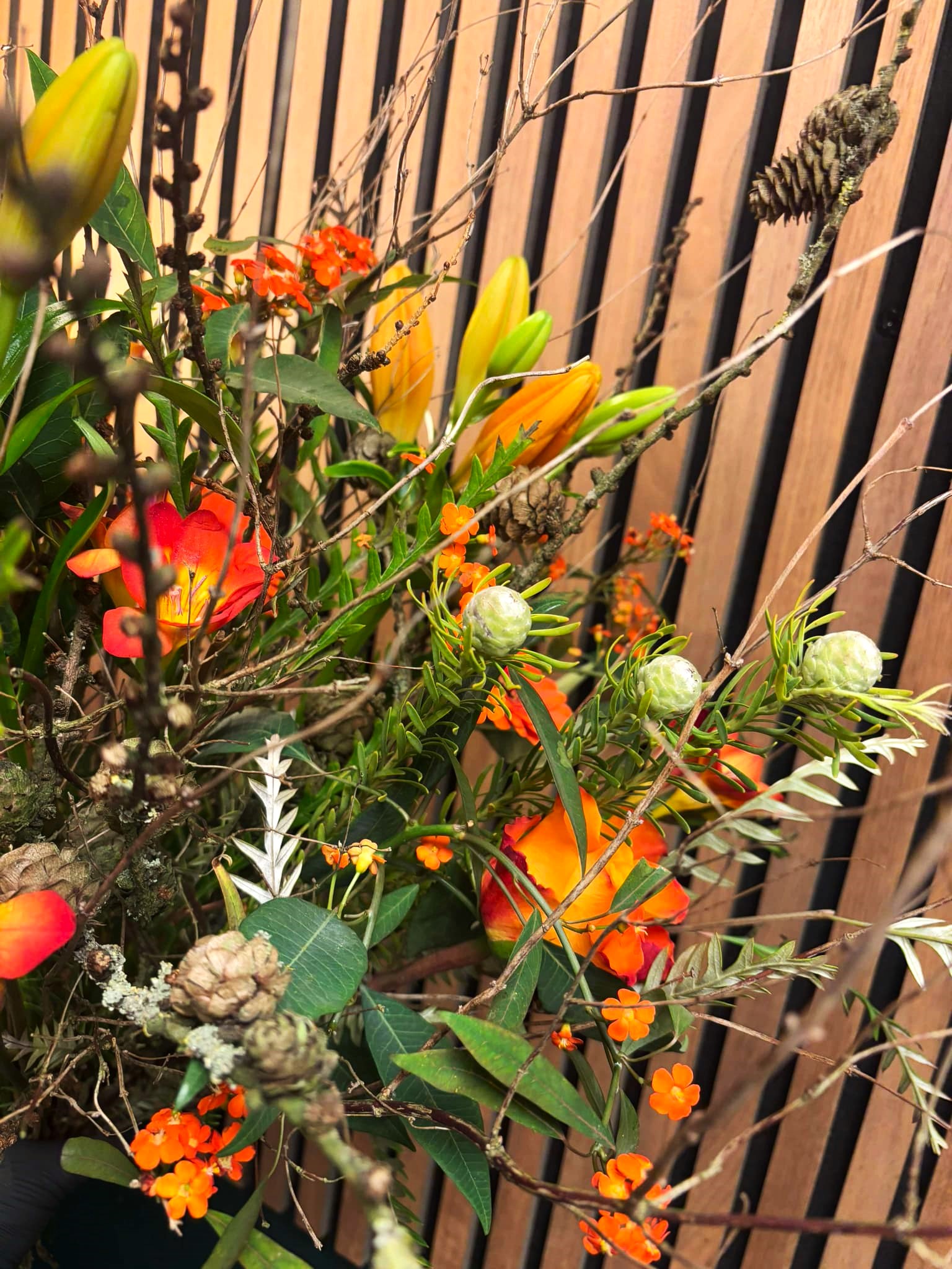 Naturlig og vild buket bundet med blomster i orange og varme nuancer. 