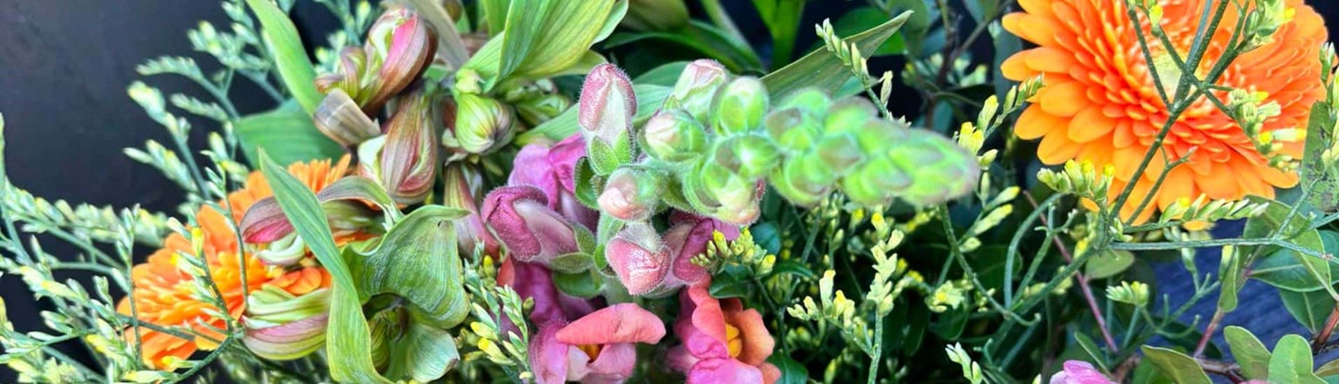Bugges varme sommerbuket med blomster i orange og, lilla og lysegrønne nuancer.