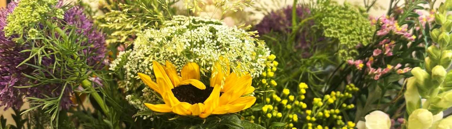 Luftig og naturlig buket med sprudlende og farverige blomster.